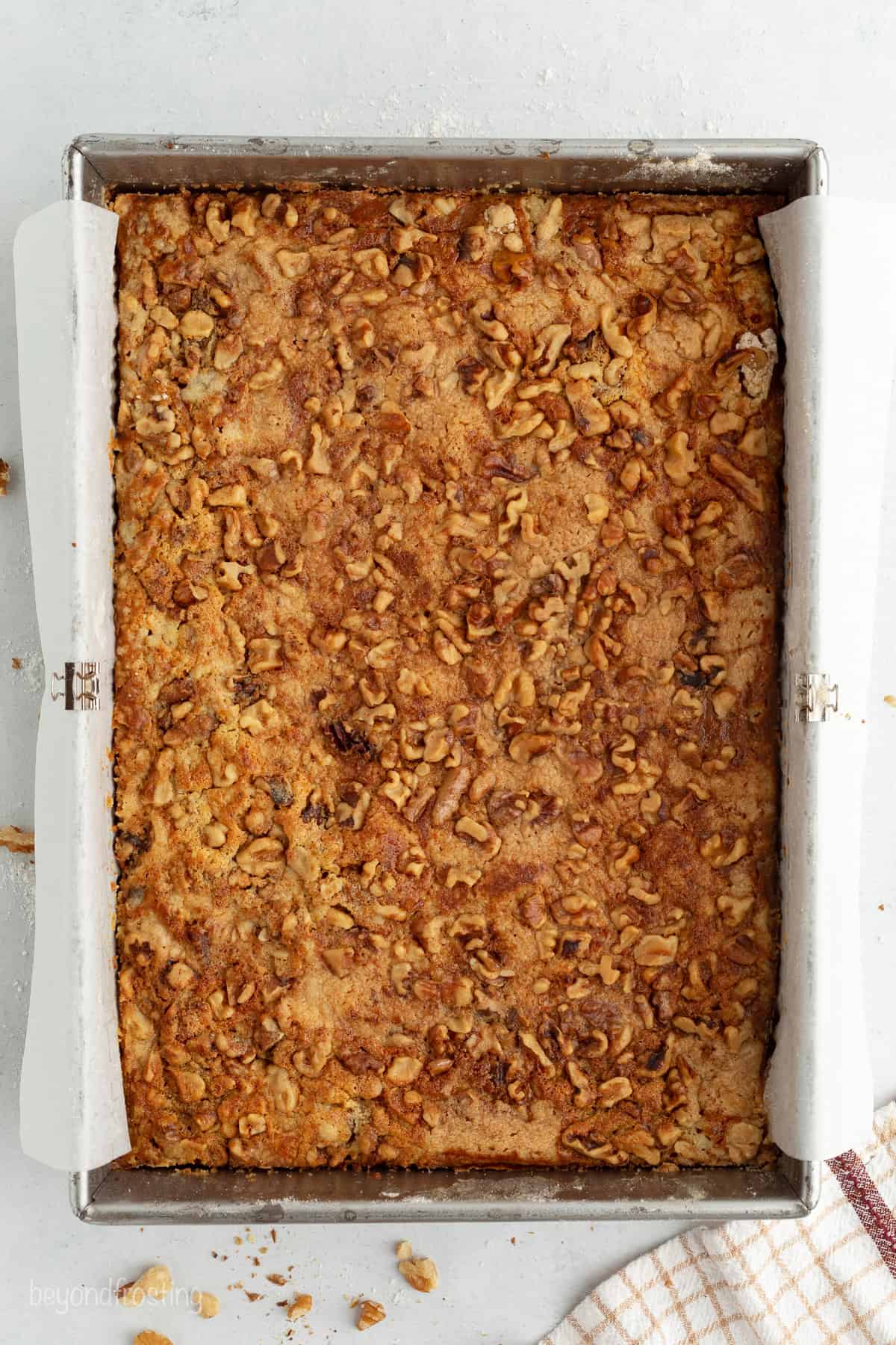 Fall pumpkin crunch cake is an easy, dump cake-style dessert with rich pumpkin filling and a buttery, crunchy cake mix layer with walnuts. Overhead view of baked pumpkin crunch cake in a baking pan.