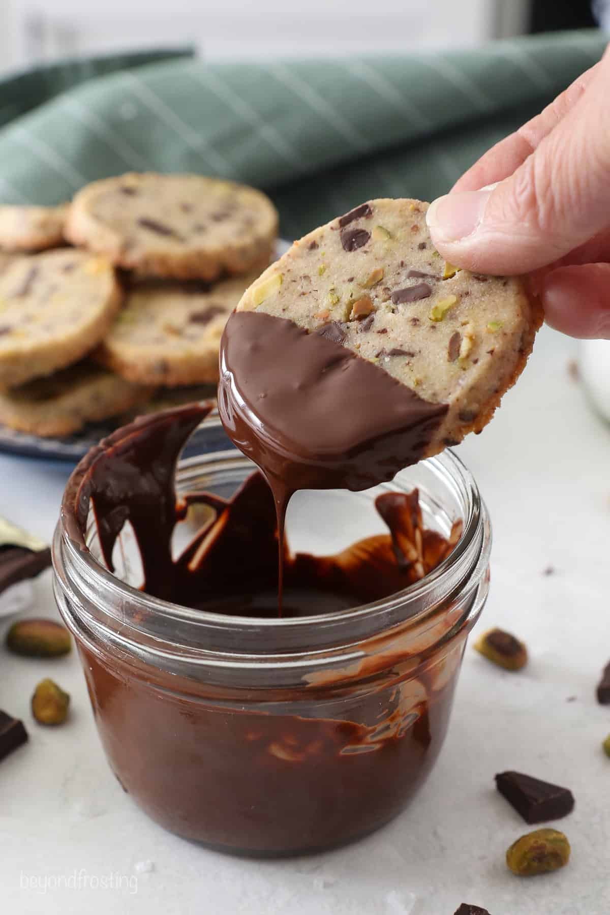 Dipping a pistachio shortbread cookie into melted chocolate.