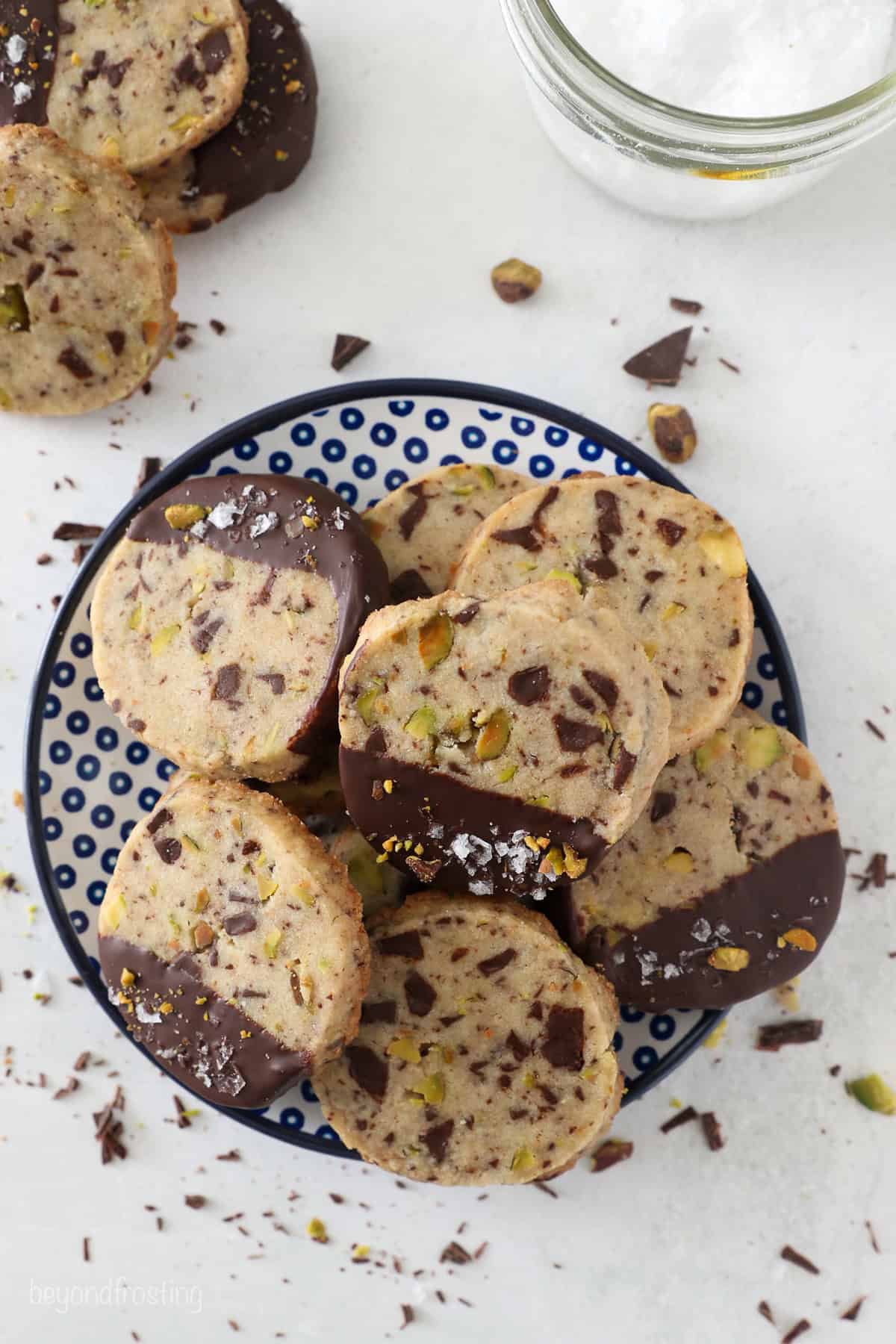 Overhead view of chocolate pistachio shortbread cookies piled on a plate.